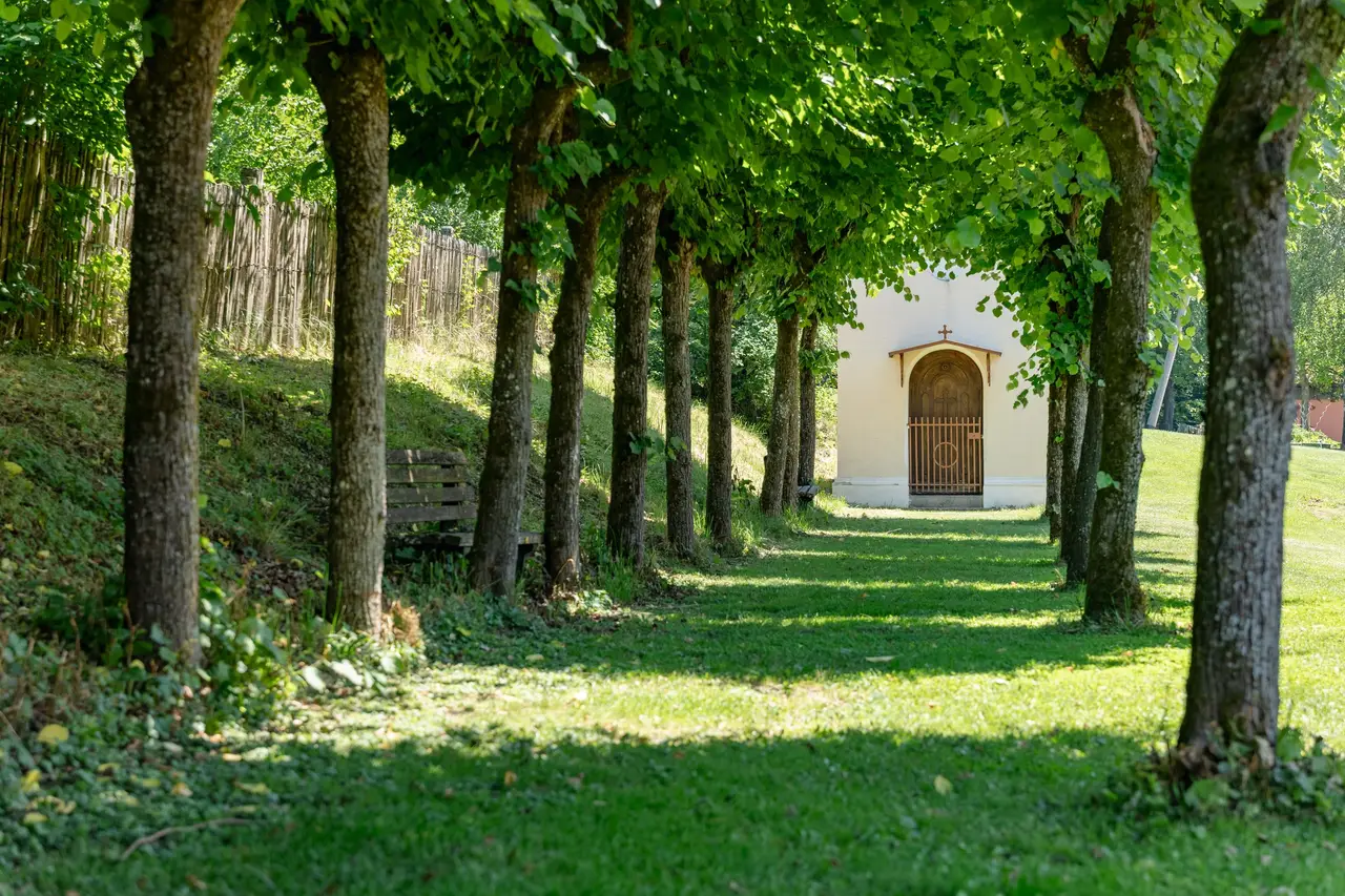 Lindenallee im Garten, an deren Ende eine kleine Kapelle steht