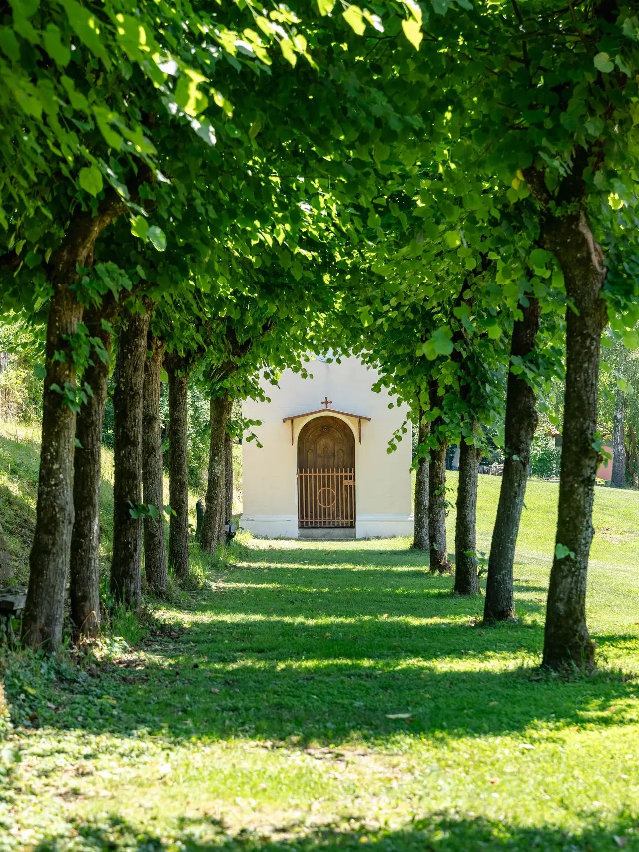 Lindenallee im Garten, an deren Ende eine kleine Kapelle steht
